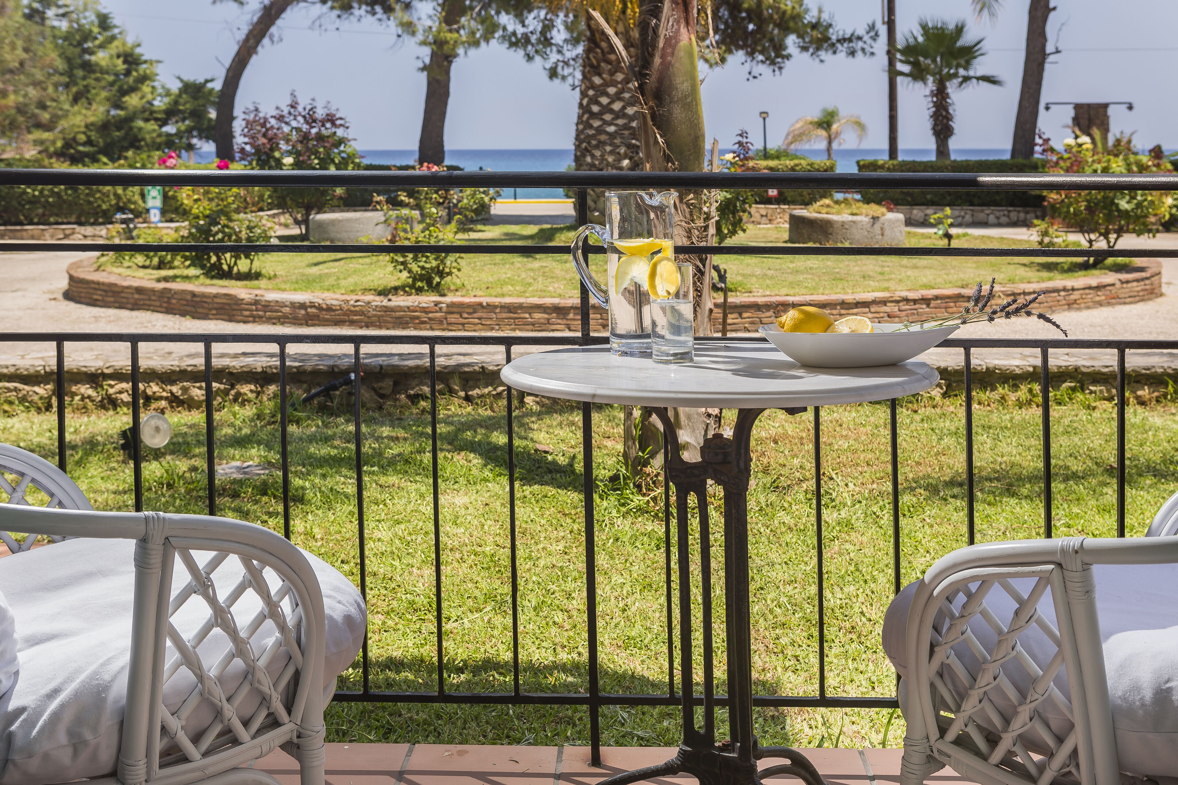 A balcony with a table, chairs, and a view of the sea.