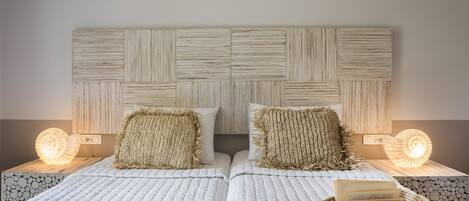 A double bed with a textured headboard, two bedside lamps, and a woven basket on the nightstand.