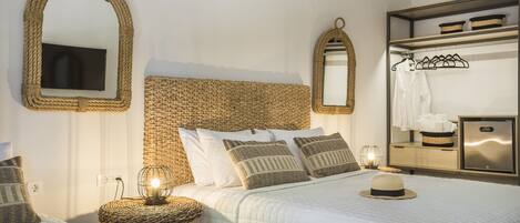A hotel room with a large bed, a television, a mirror, and a wardrobe.