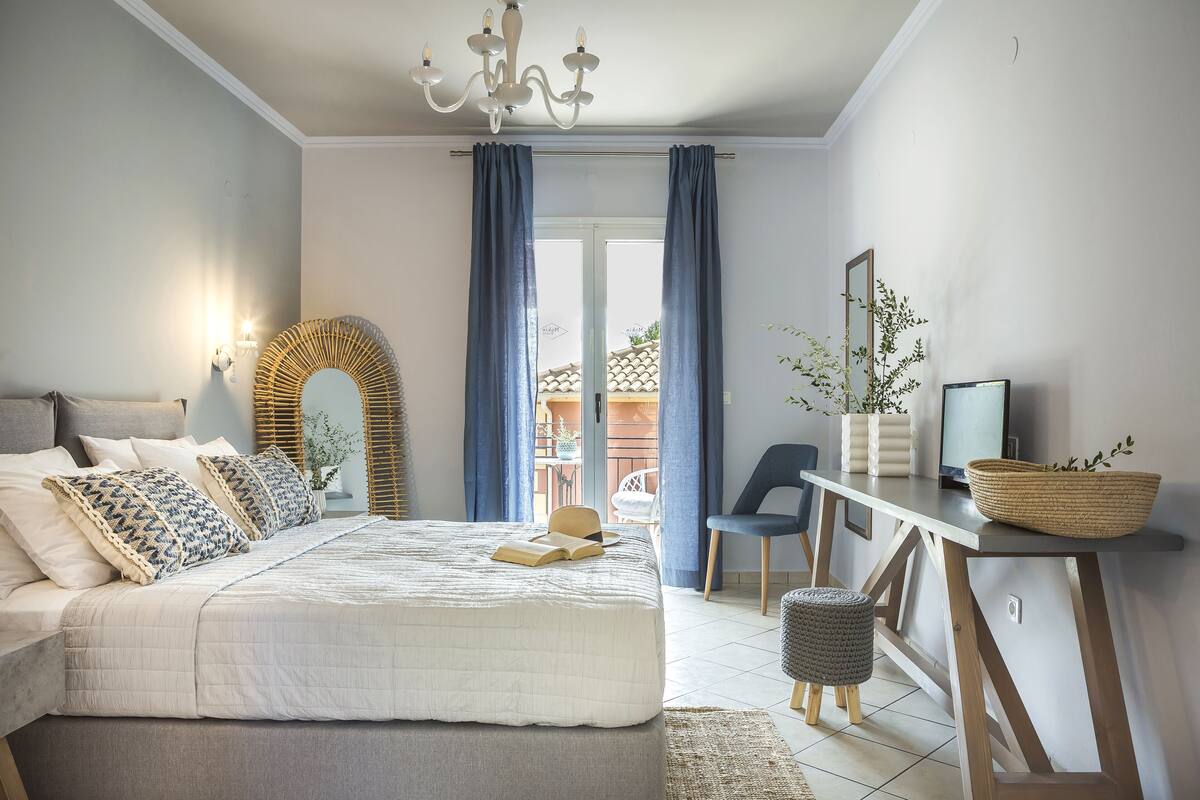 A bedroom with a bed, bedside table, chair, and a view of the outside.