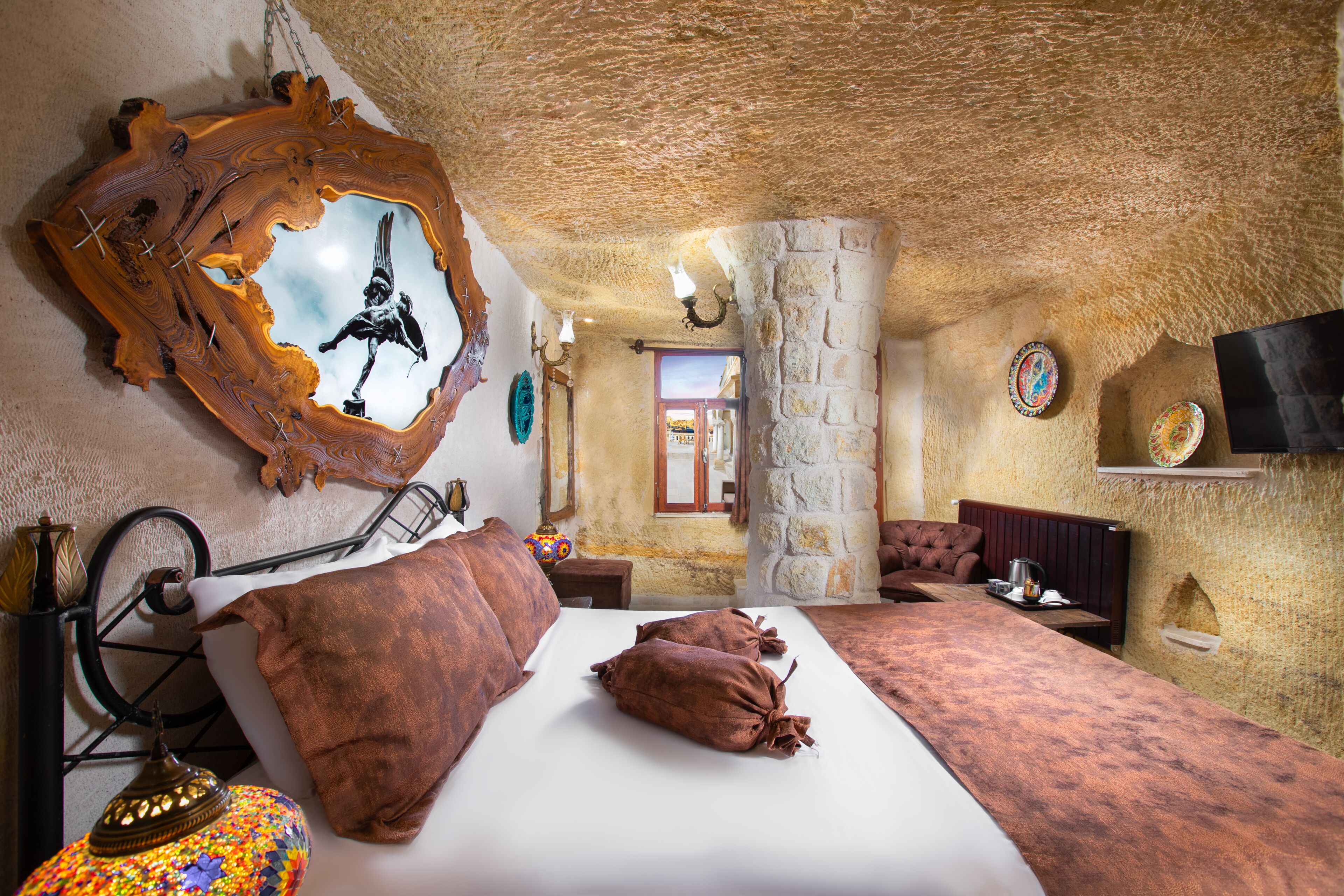 Un dormitorio con cama, espejo, lámpara y televisión.