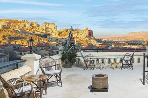 Una terraza en la azotea con sillas de mimbre, una mesita y un árbol de Navidad.