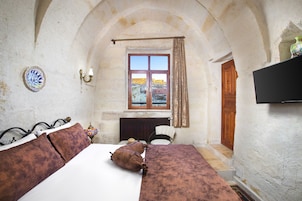 Una habitación pequeña con una cama, una silla, una ventana y un televisor.