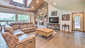 A spacious living room with a leather sectional sofa, a wooden coffee table, a fireplace, and a television.