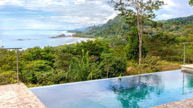 An infinity pool with a clear view of the ocean and a lush green landscape. - Luxe 4 Bdrm Villa w Epic Oceanview Infinity Pool (Bahía Ballena)