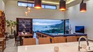 A modern dining area with a large table, wicker chairs, and a view of the ocean. - Luxe 4 Bdrm Villa w Epic Oceanview Infinity Pool (Bahía Ballena)