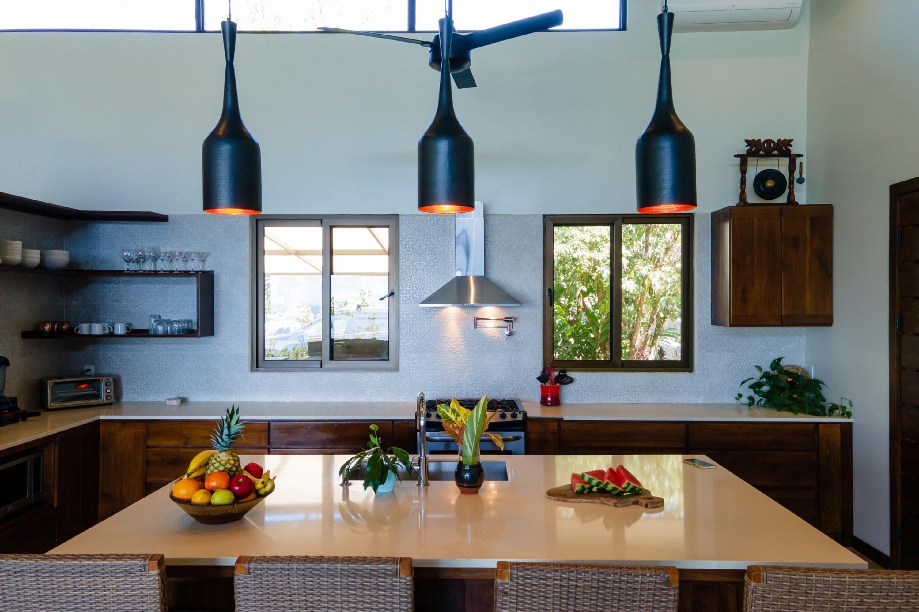 A modern kitchen with a central island, wooden cabinets, and pendant lighting.