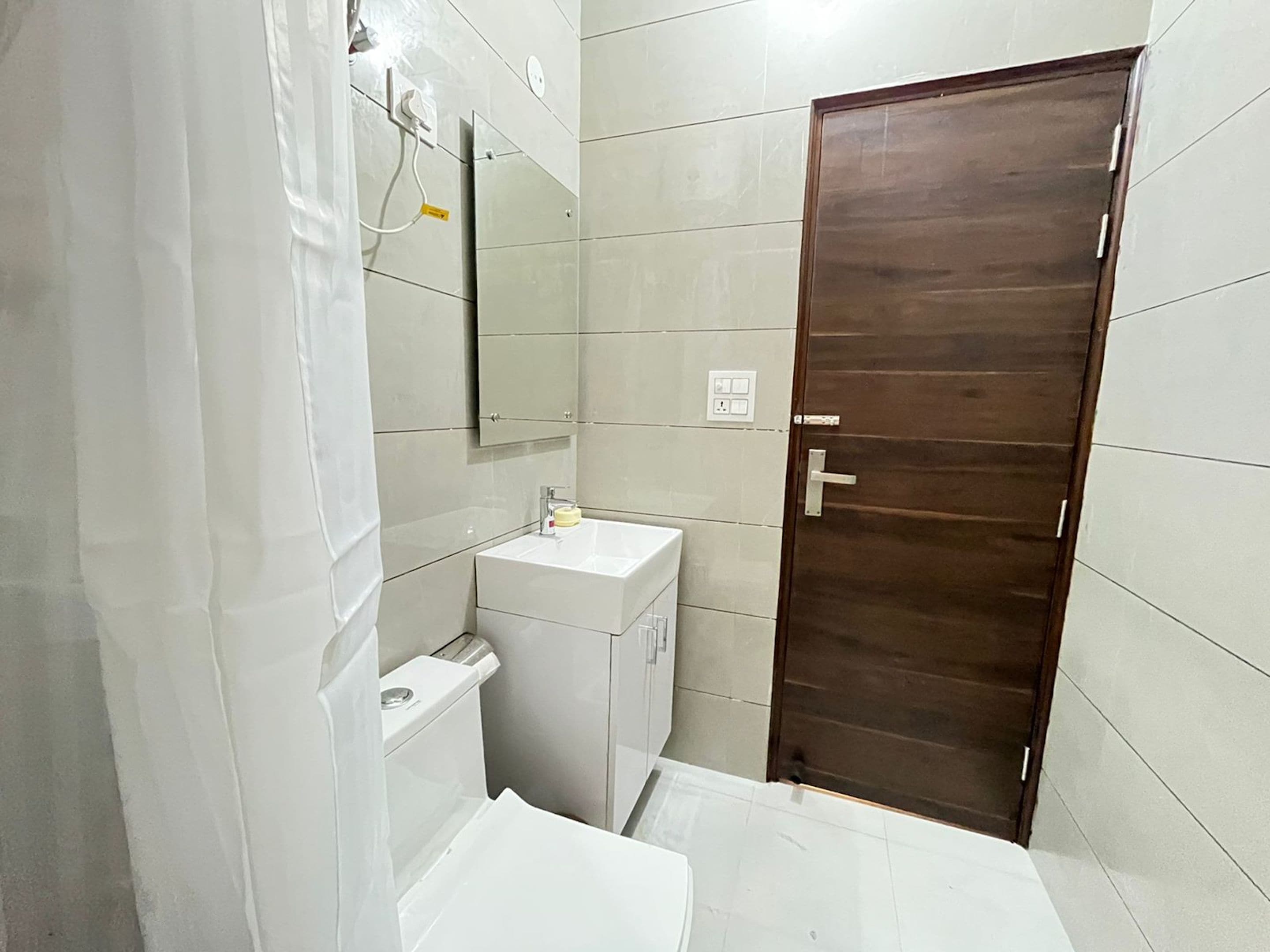 Et badeværelse med en hvid vask, spejl og toilet.