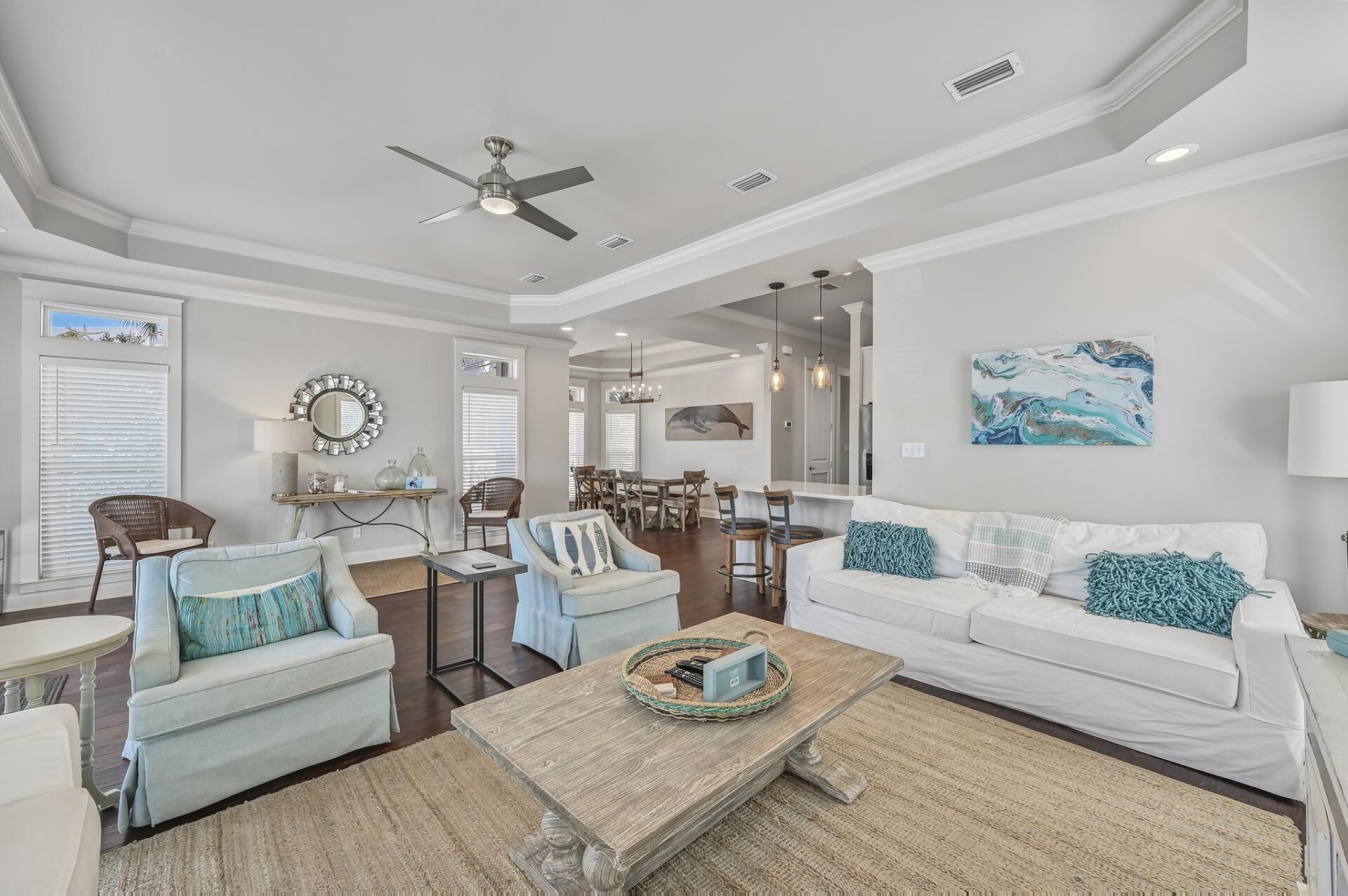 A spacious living room with a white sofa, two armchairs, a coffee table, and a dining area in the background.
