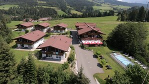 Ein Hotel mit mehreren Chaletgebäuden, einem Parkplatz und einem Schwimmbad.