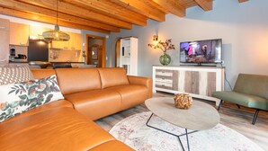Ein modernes Wohnzimmer mit einer Ledersofa, einem runden Couchtisch und einem Fernseher auf einer Holzkommode.