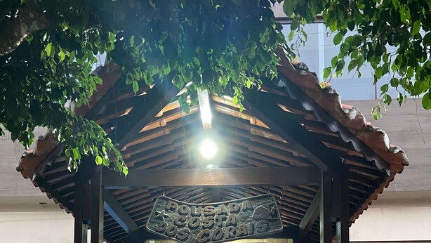 Ein überdachter Eingangsbereich mit einer Holz-Pergola, einem Fliesenboden und einem Wandgemälde von Fischen.