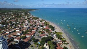 Luftaufnahme einer Küstenstadt mit Strand, Booten und Wohnhäusern.