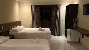 Ein Hotelzimmer mit zwei Betten, einem kleinen Kühlschrank und einem Spiegel.