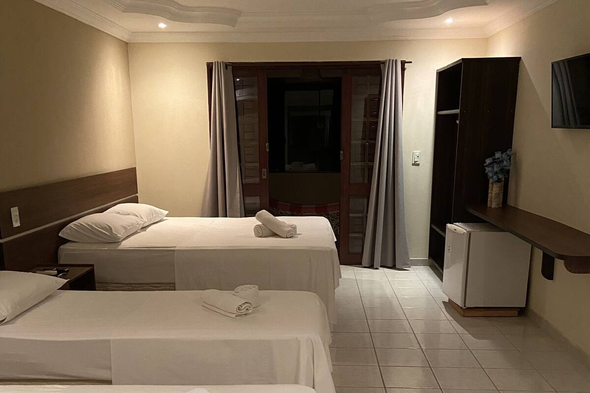 Une chambre d’hôtel avec deux lits, un petit réfrigérateur et un miroir.