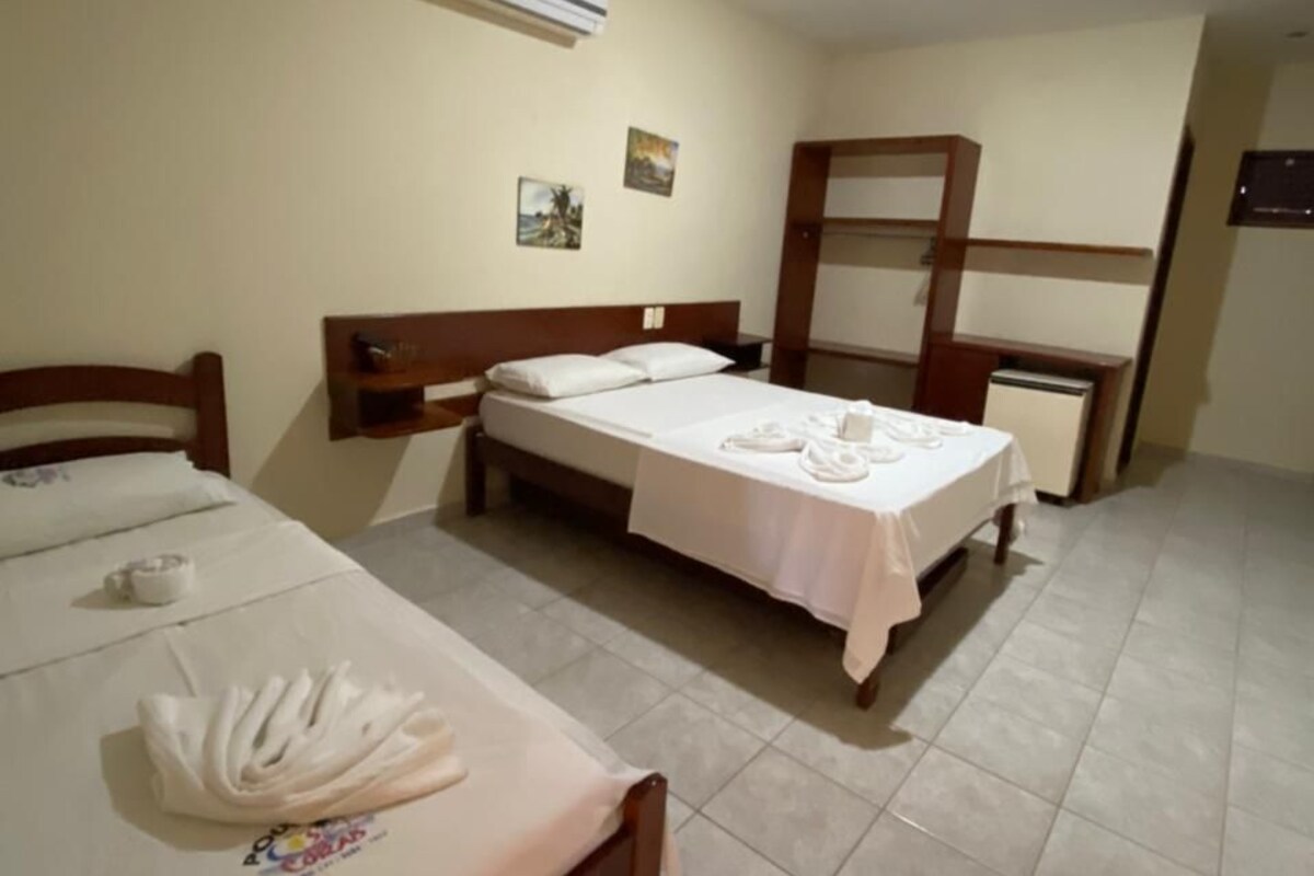 Habitación de hotel con dos camas, un cabecero de madera, un escritorio pequeño y un equipo de aire acondicionado en la pared.