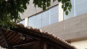 Ein überdachter Außenbereich mit einer Holzpergola, Steinstufen und Kübelpflanzen.