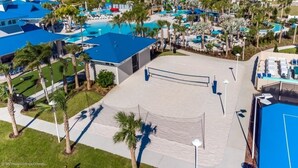 Un resort con varias piscinas, palmeras y una cancha de tenis.