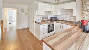 A modern kitchen with white cabinets, a wooden countertop, a built-in oven, a microwave, and a toaster. - Host & Stay | The Duck Pond (Durham)