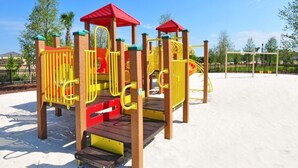 A playground with a slide, climbing structures, and a red-roofed playhouse. - Amazing 4br Resort Townhome W/ Splash Pool-4686td 4 Bedroom Villa by RedAwning (Davenport)