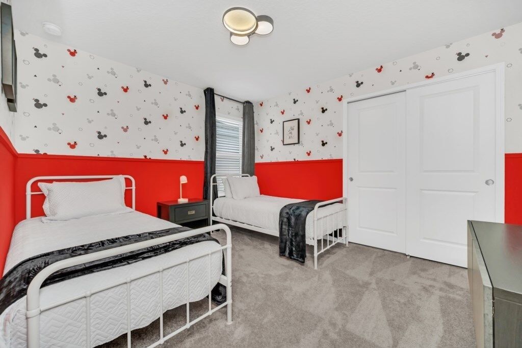Ein Schlafzimmer mit zwei Betten, einem Kleiderschrank, einem Spiegel und einer Tür.