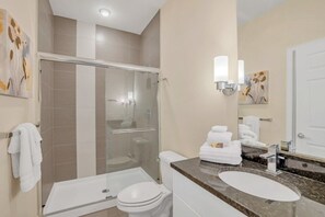 A modern bathroom with a glass-enclosed shower, a white toilet, and a marble sink. - 1511retreat 3 Bedroom Townhouse by Redawning (Clermont)