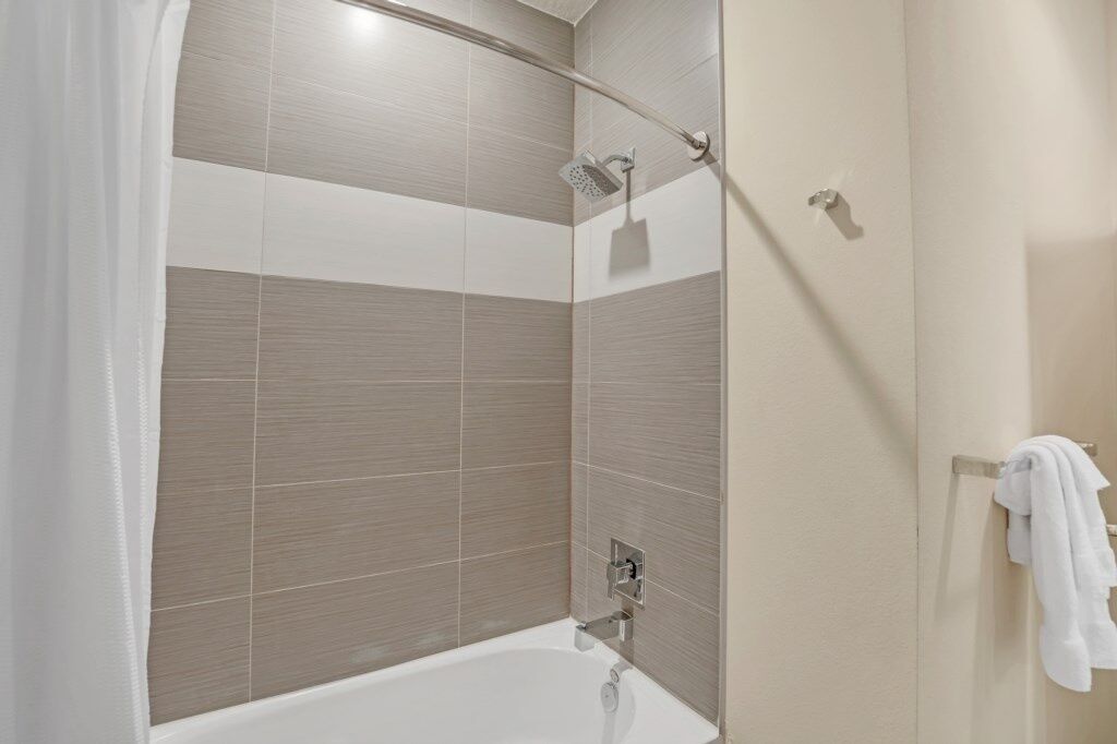A modern bathroom with a shower, a bathtub, and a towel rack.