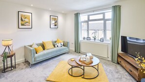 A living room with a sofa, a coffee table, a lamp, and a TV. - Host & Stay | Morgan's Rest (Scarborough)