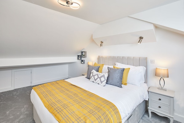 A bedroom with a bed, bedside tables, a nightstand, and a ceiling light fixture.