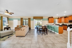 Relax in this inviting living space with a sofa, ottoman, dining table, and kitchen island.
