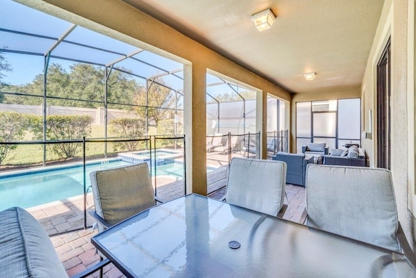 Relax by the pool in this serene outdoor space, featuring a glass table and comfortable seating.
