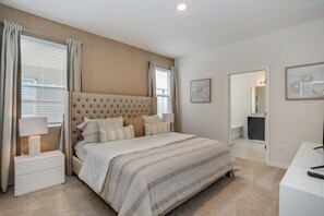 A bedroom with a large bed, a nightstand, a desk, and a mirror.
