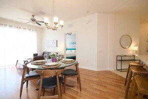 A dining area with a round table, wooden chairs, and a ceiling fan.