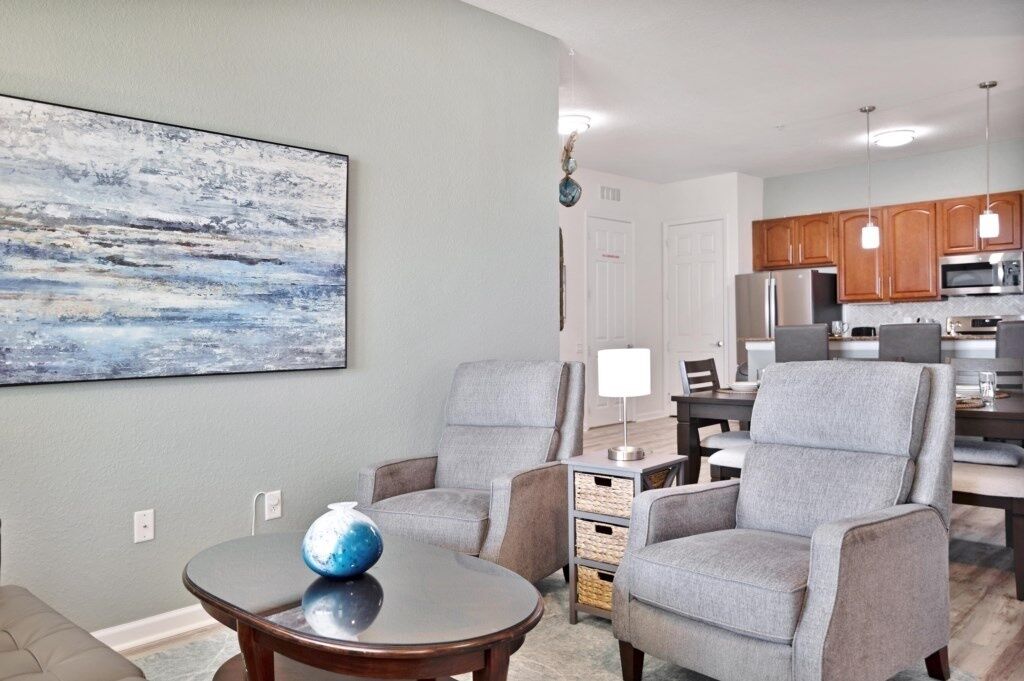 A living room with a sofa, armchairs, a coffee table, and a painting on the wall.