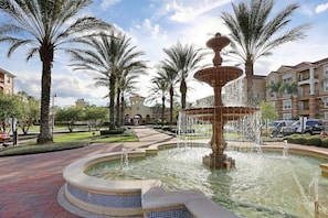 Stroll through a serene outdoor oasis with a central fountain and palm trees.