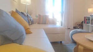 Un salón con un sofá blanco, una mesa redonda y una estantería.