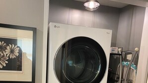 Een gestapelde wasmachine en droger in een wasserij, met een ingelijst beeld aan de muur.