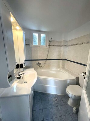 Et badeværelse med badekar, toilet og vask.