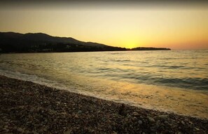 A pebbled beach with a sunset over the water and distant hills. - Live the Summer Dream at Gaios Cozy Retreat (Gaios)