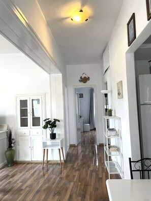 A spacious kitchen with wooden flooring, white cabinetry, and a central island.