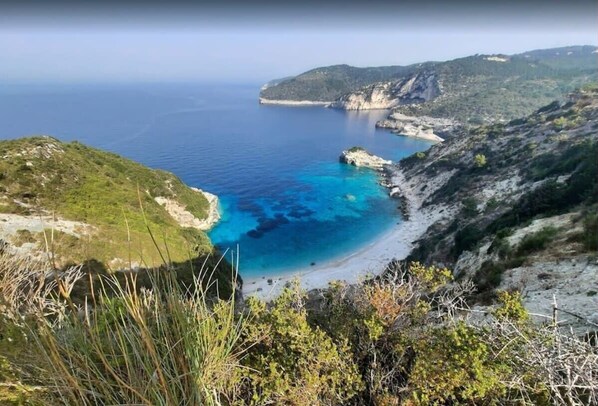 A coastal landscape with a clear view of the sea, rocky terrain, and vegetation.