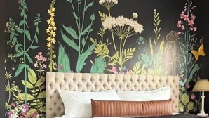 A bedroom with a tufted headboard, a bed with a black and white striped bedspread, and a nightstand with a lamp.