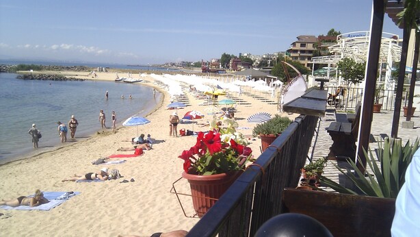 A beach with sun loungers and umbrellas, a railing, and potted plants. - Stunning Apartment With Pool in Ravda, Bulgaria (Nessebar)