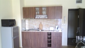 A compact kitchen with wooden cabinets, a built-in microwave, a refrigerator, and a toaster. - Stunning Apartment With Pool in Ravda, Bulgaria (Nessebar)