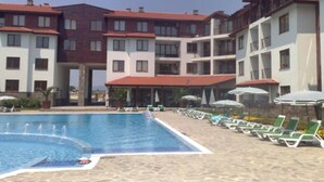 A hotel with a swimming pool surrounded by lounge chairs and umbrellas. - Stunning Apartment With Pool in Ravda, Bulgaria (Nessebar)