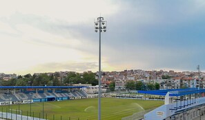 A stadium with blue seating and a floodlight tower. - Apart-Hotel Onegin (Sozopol)