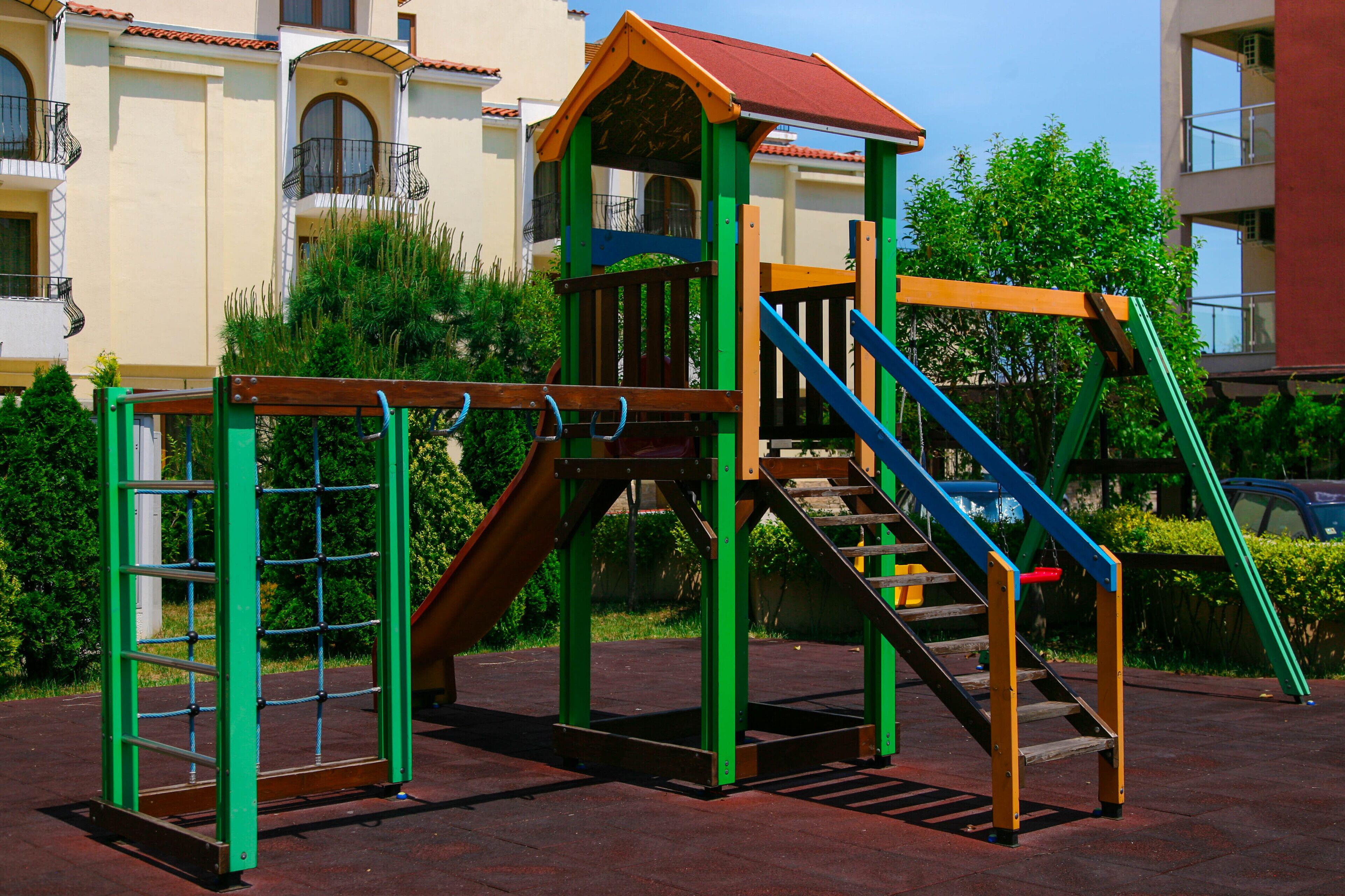 A playground with a climbing structure, slides, and stairs.