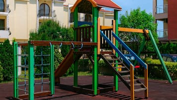 A playground with a climbing structure, slides, and stairs.