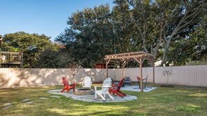 Un pati amb una pèrgola de fusta, mobiliari exterior amb cadires Adirondack i una xemeneia.