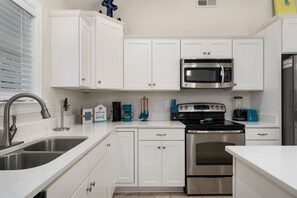 A modern kitchen with white cabinets, stainless steel appliances, and a double sink.